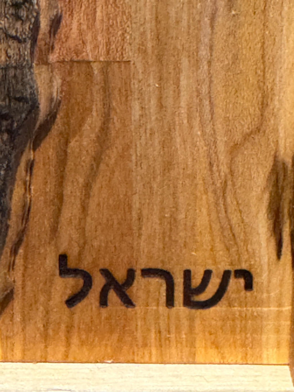 A detailed close-up of the lower section of the wood map, featuring the Hebrew word for Israel ("ישראל") cleanly engraved in a bold, classic font into the rich grain of the hardwood. __etsy:8204351127