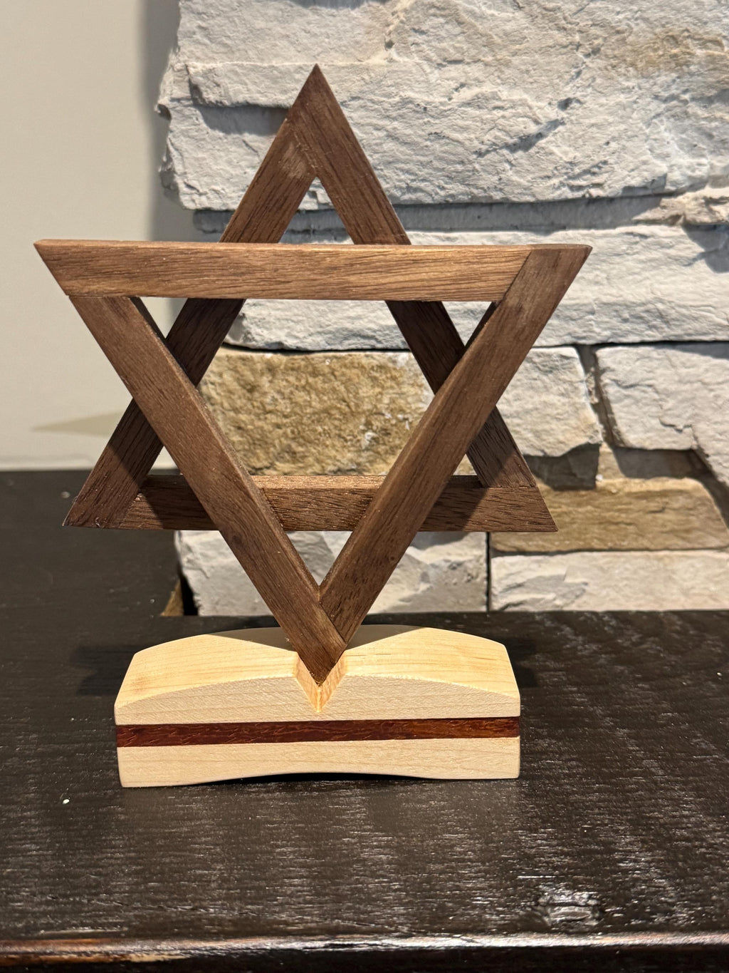 Front-facing view of a handcrafted wooden Magen David (Star of David) standing upright on a matching multi-toned wood base. The geometric star sculpture features a distinct three-dimensional interlocking design made from contrasting light and dark natural hardwoods. __etsy:8204394375