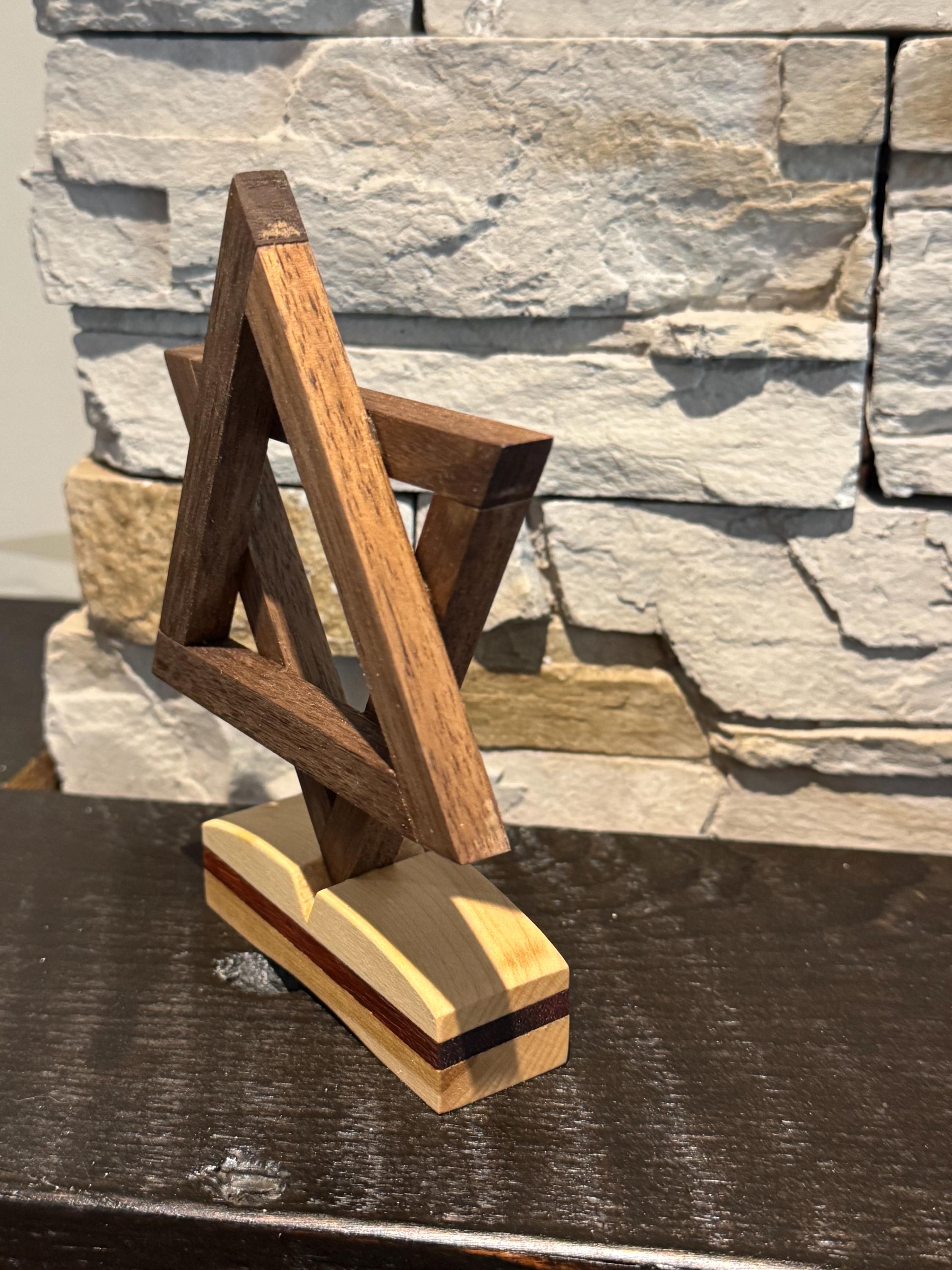 An angled three-quarter view of the wooden Magen David sculpture, beautifully showcasing the vibrant reddish-orange hues of the Padauk wood intertwined with darker walnut and lighter maple wood tones. __etsy:8156470436