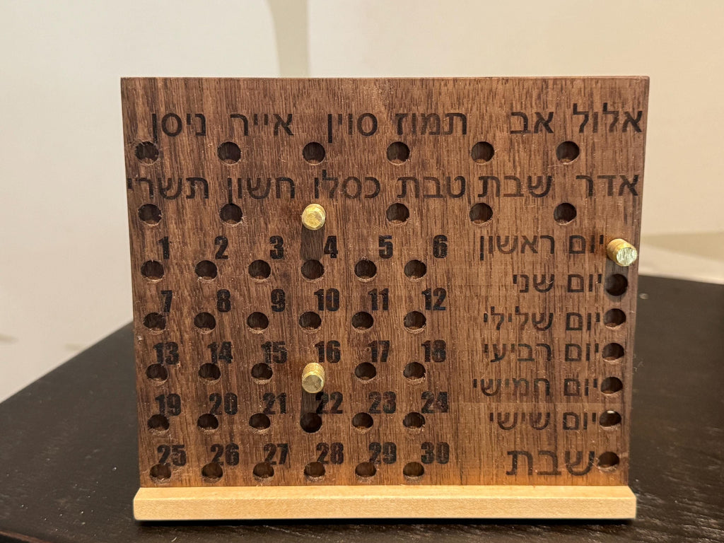 Front view of a handcrafted wooden Hebrew perpetual calendar showing engraved Hebrew months and days, with adjustable bronze pins marking the date. __etsy:8204556623