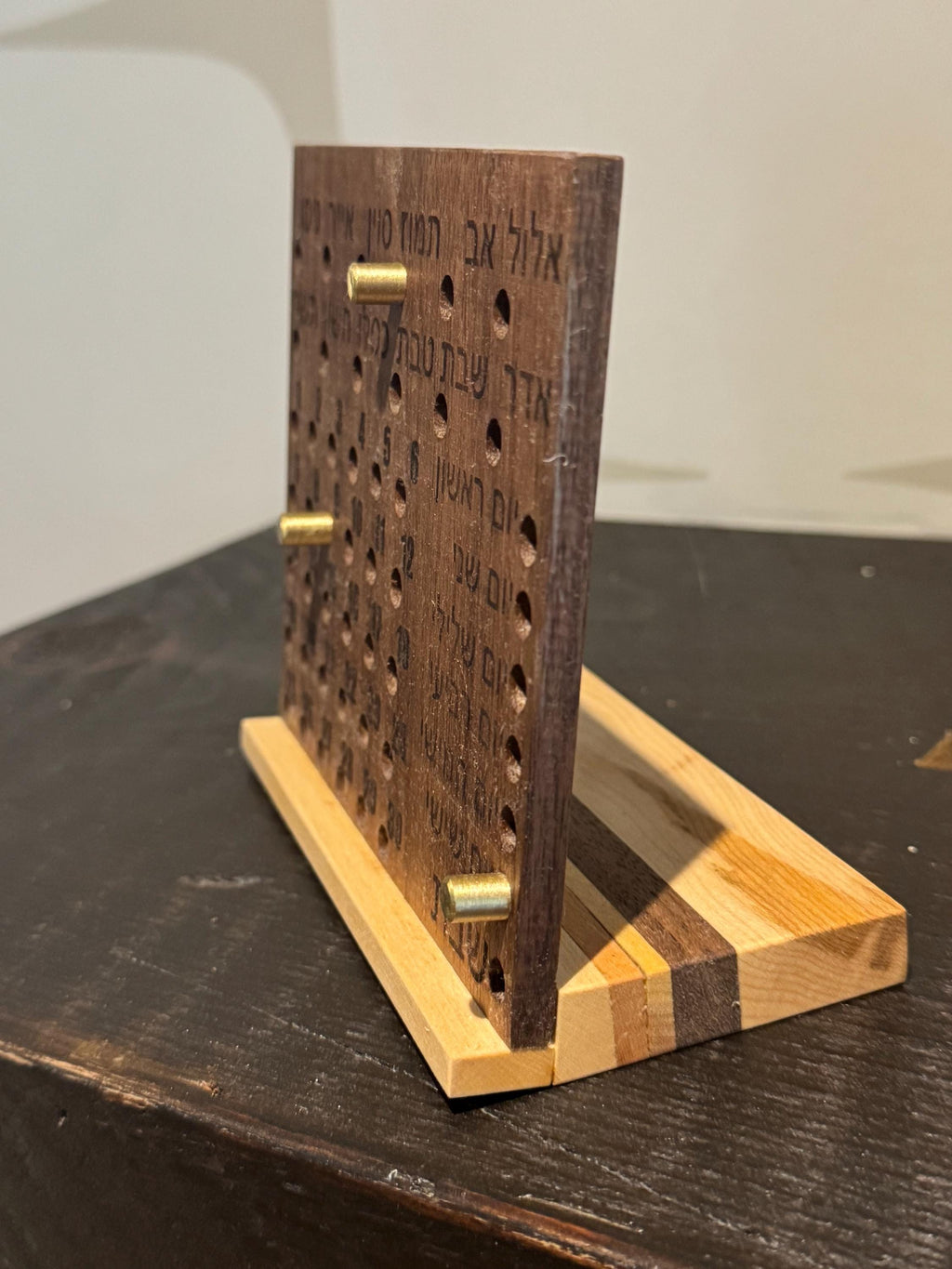 Side angle view of a wooden Hebrew perpetual calendar, showcasing the natural wood grain and the angled desk-stand design. __etsy:8204555917