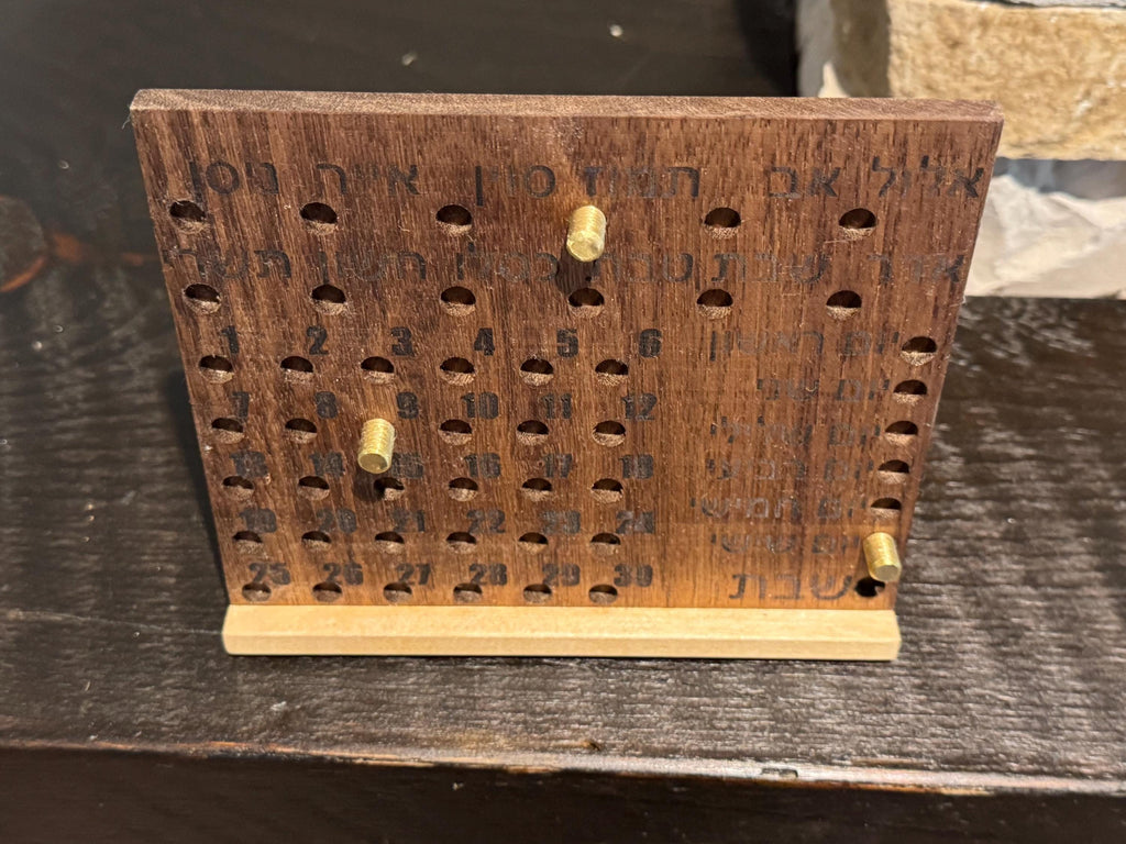 Straight-on front view of a rectangular wooden Hebrew perpetual calendar with neat rows of engraved characters and a smooth natural finish. __etsy:8156632386
